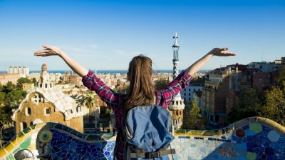 Girl looking over a city with her arms in the air