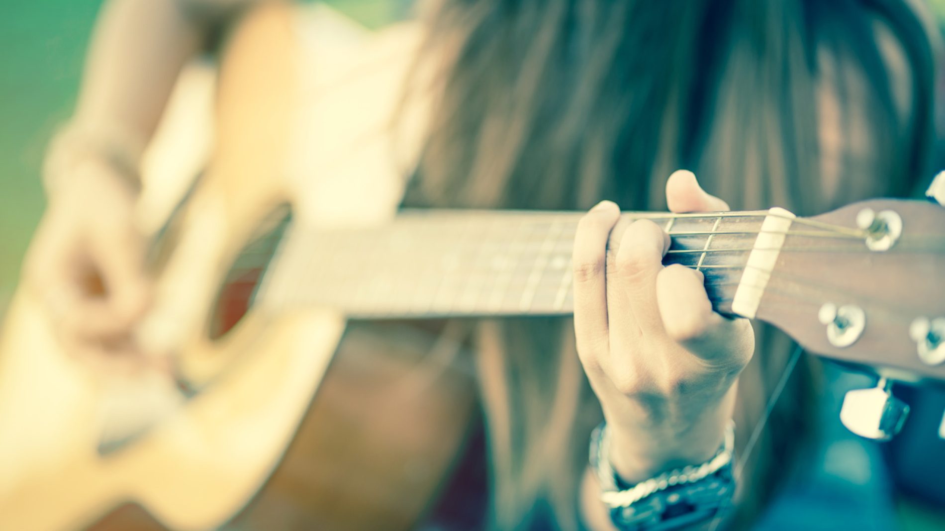 closeup of female's hands playing acoustic guitar with vintage tone