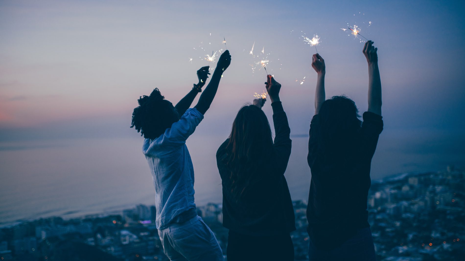 Group of young adult friends celebrate with sparklers at night