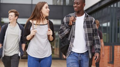 Group Of Students Walking Outside College Buildings