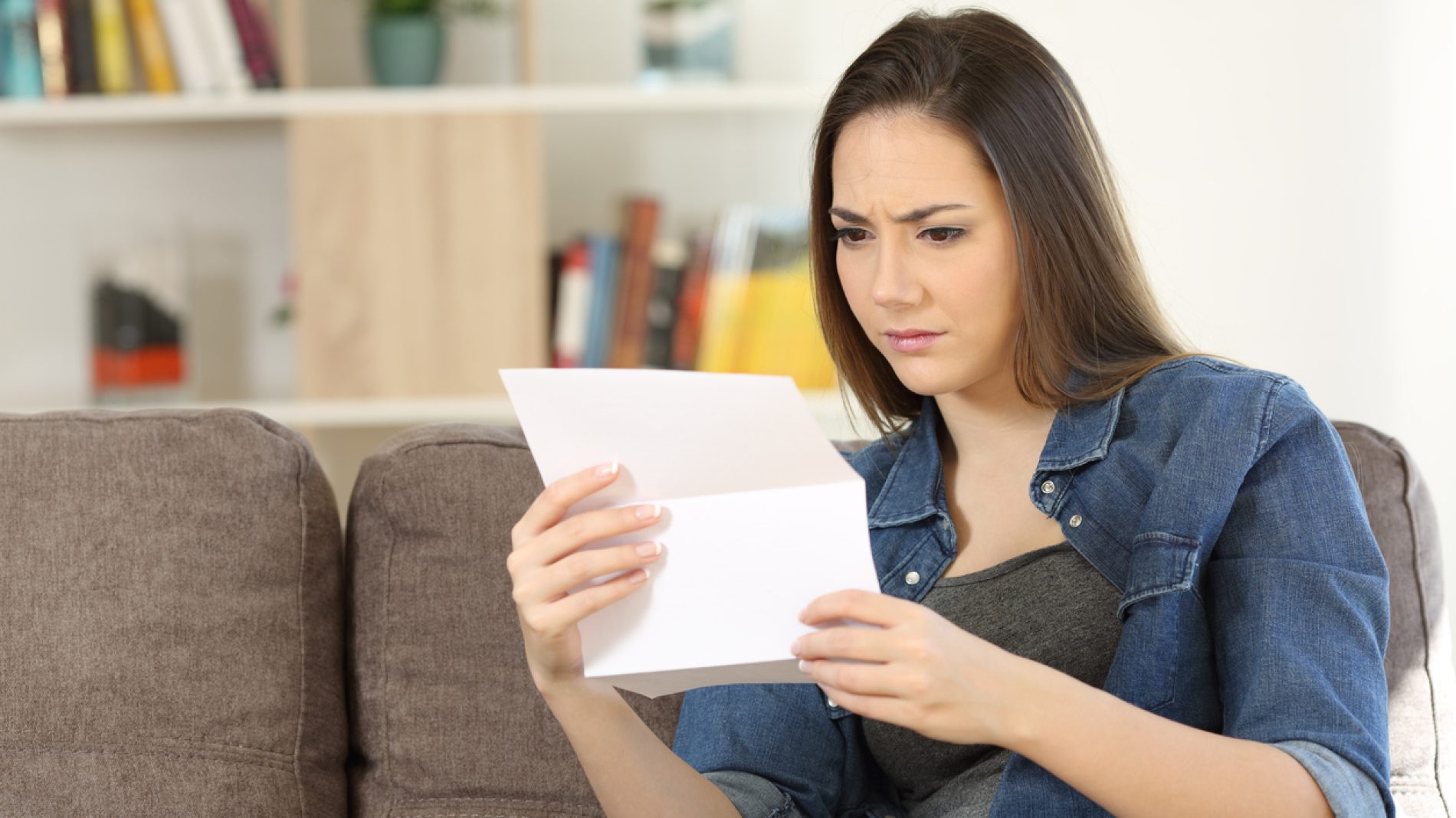 Worried woman reading a letter at home