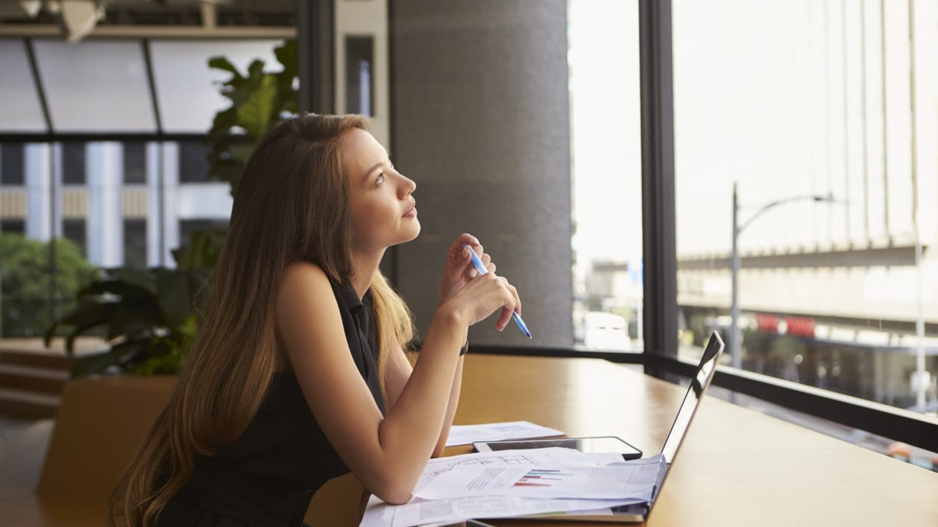 Young woman thinking while on her laptop