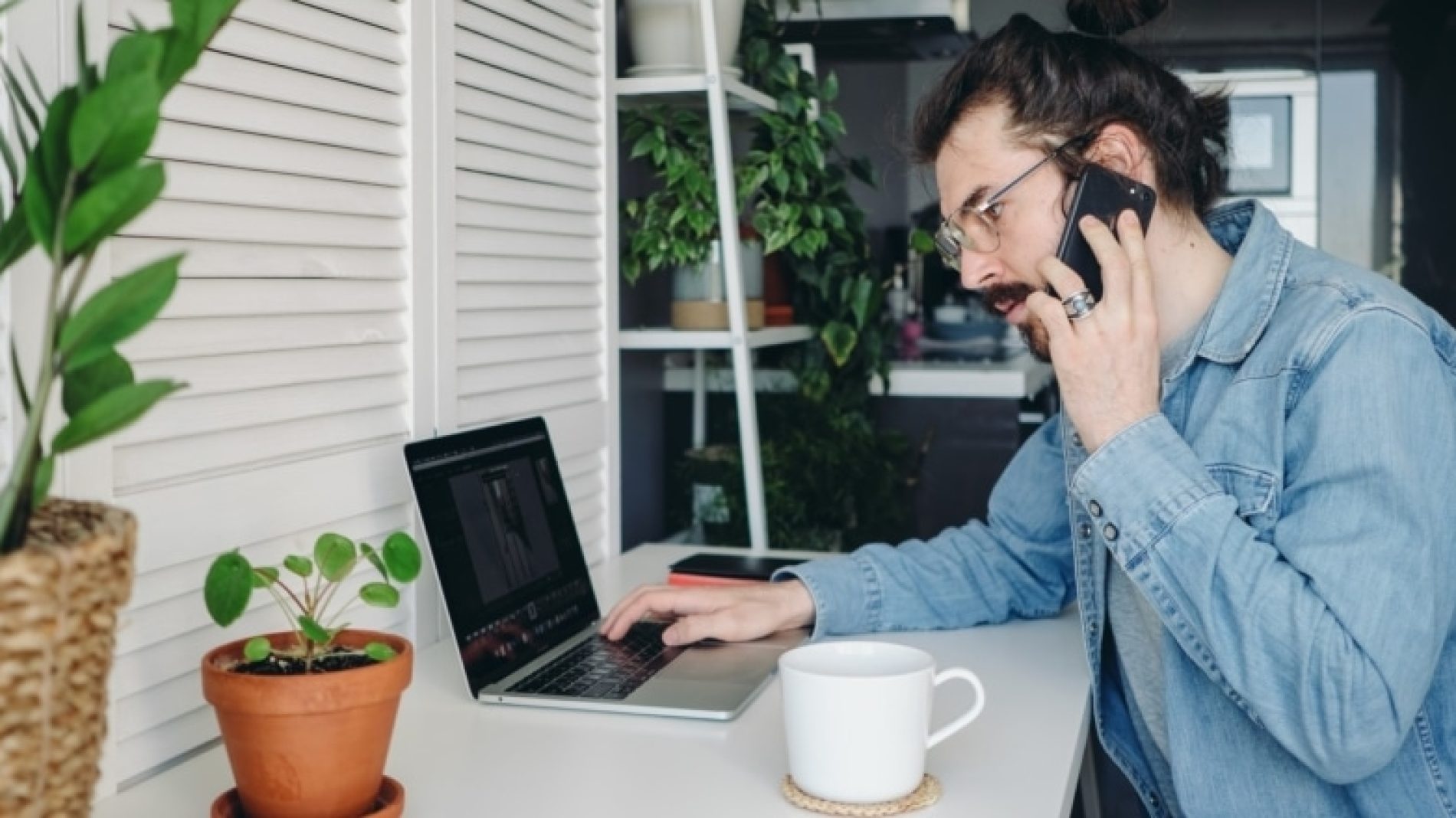 Young-man-on-laptop-and-phone-at-home-54rwZn