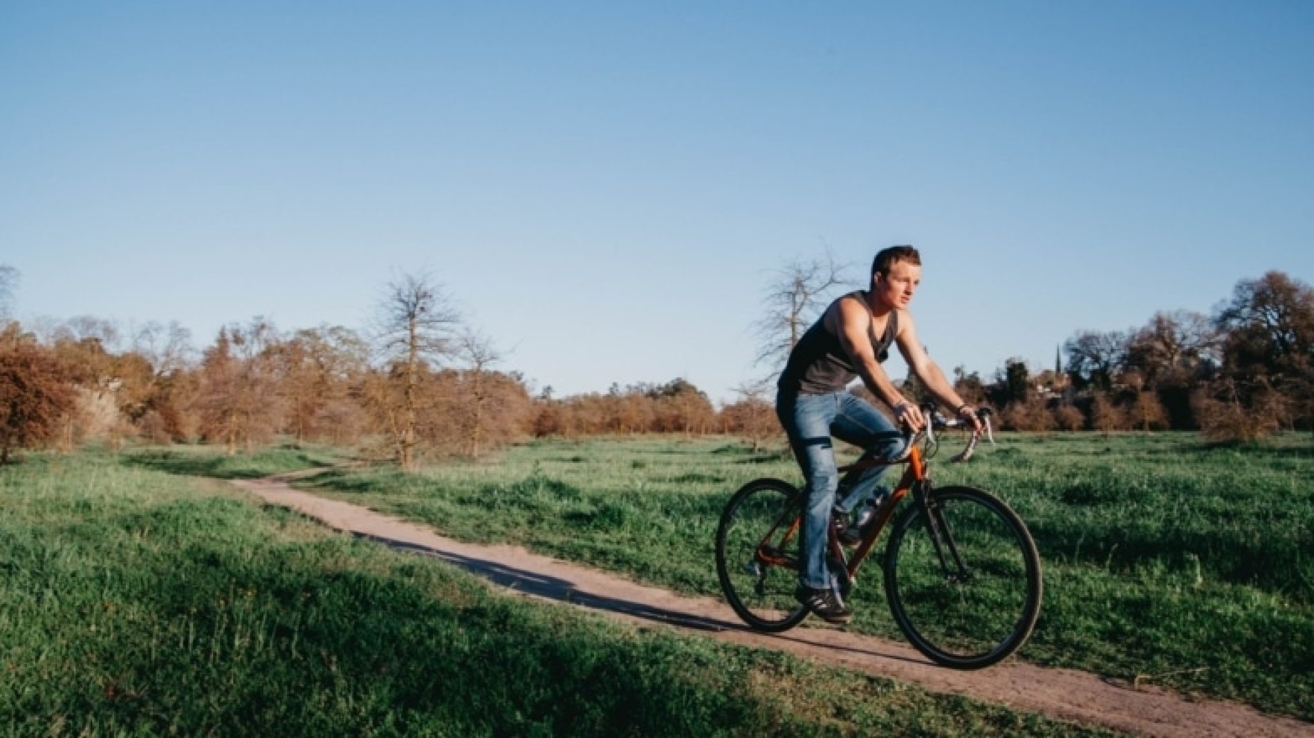 Young-person-cycling-on-their-bike-through-a-field-AsPtOq