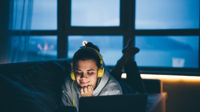 Young person listening to a podcast at night