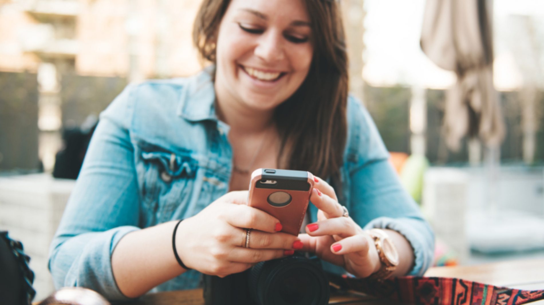 Young-person-smiling-with-phone-and-camera-9nKbMJ