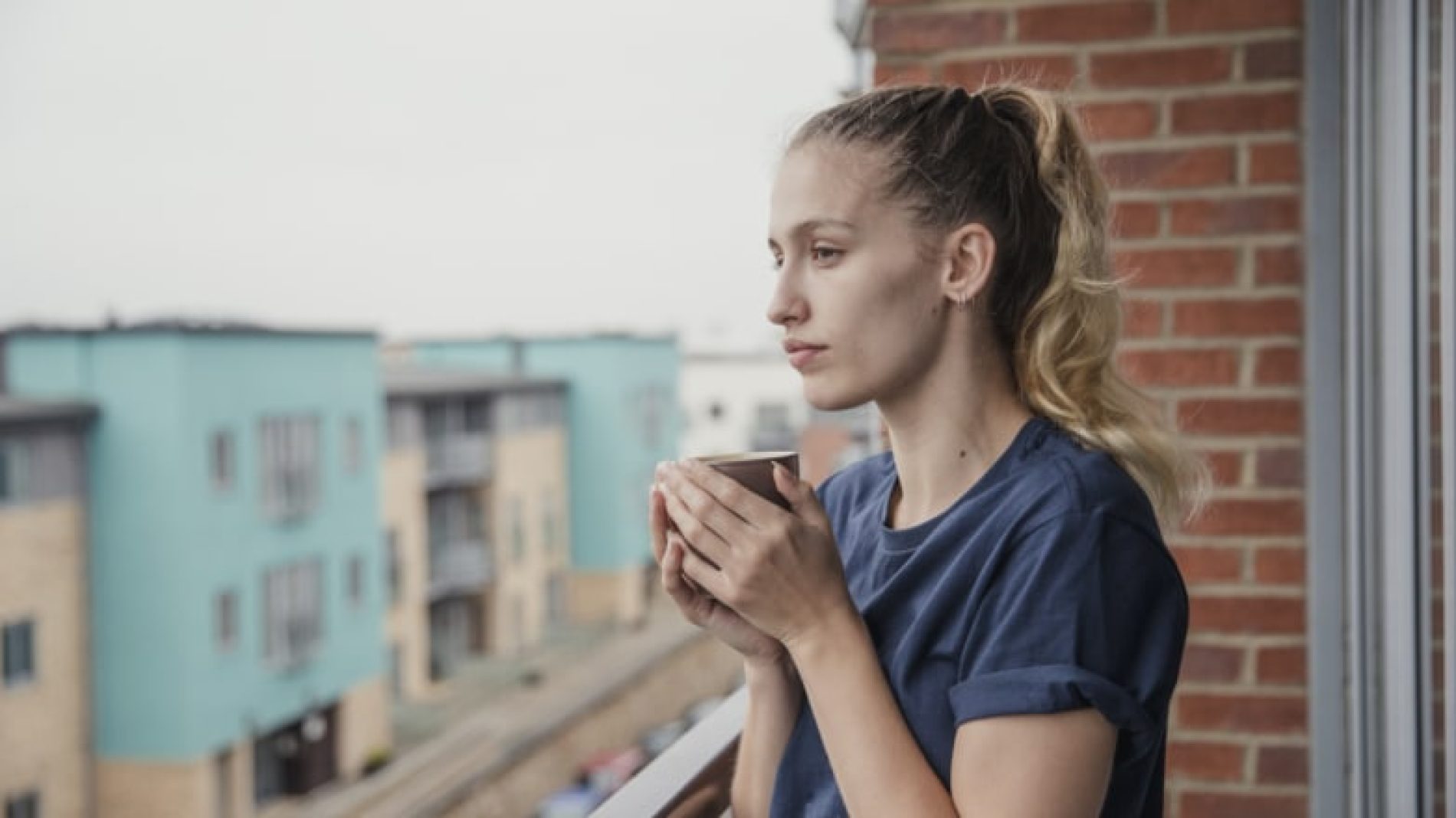 Young-woman-on-balcony-with-tea-vNnxzT
