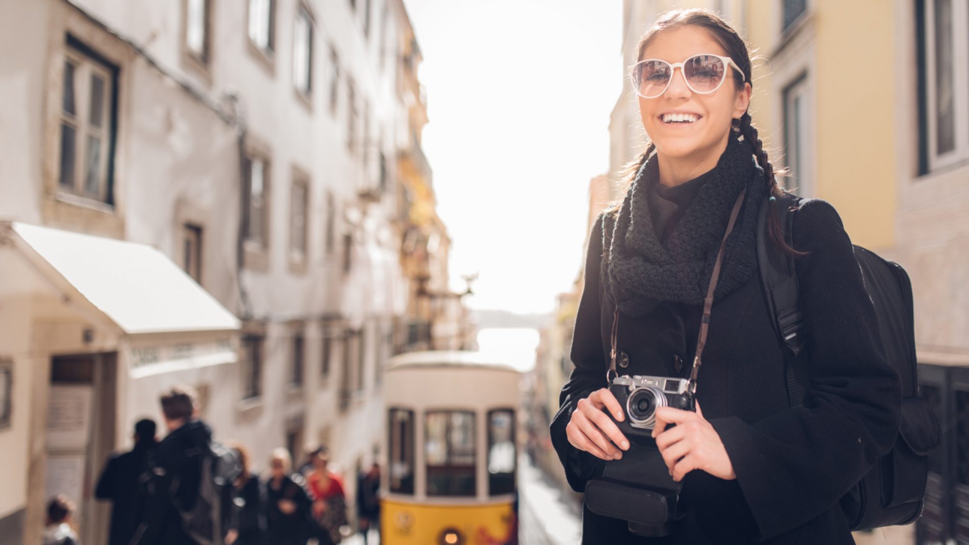 Female traveler woman sightseeing in European capital.Visitor in Lisbon,Portugal.Yellow tram route.Traveling Europe on a budget.Studying abroad.Photography and travel concept