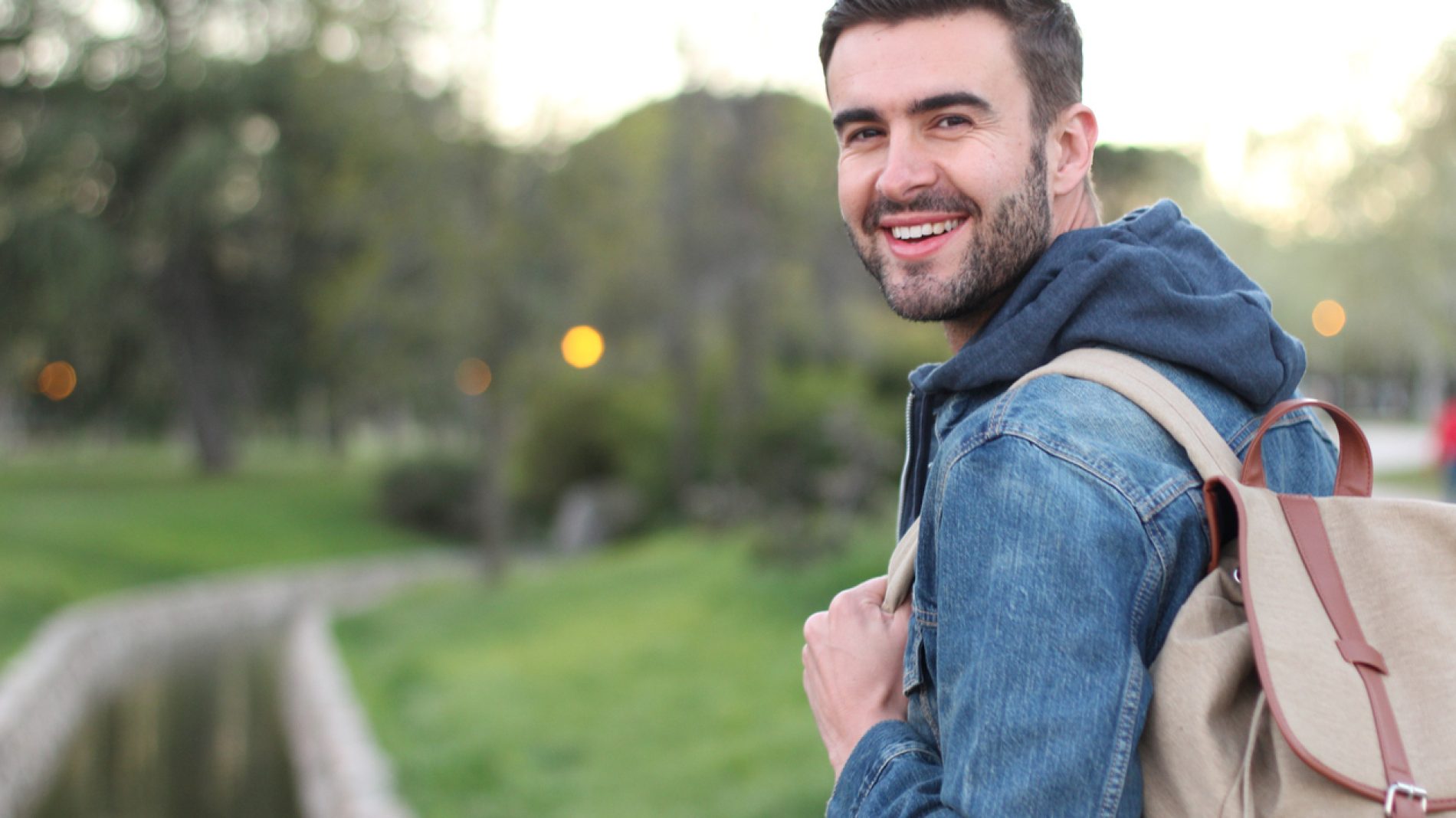 Smiley male holding backpack outdoors with copyspace