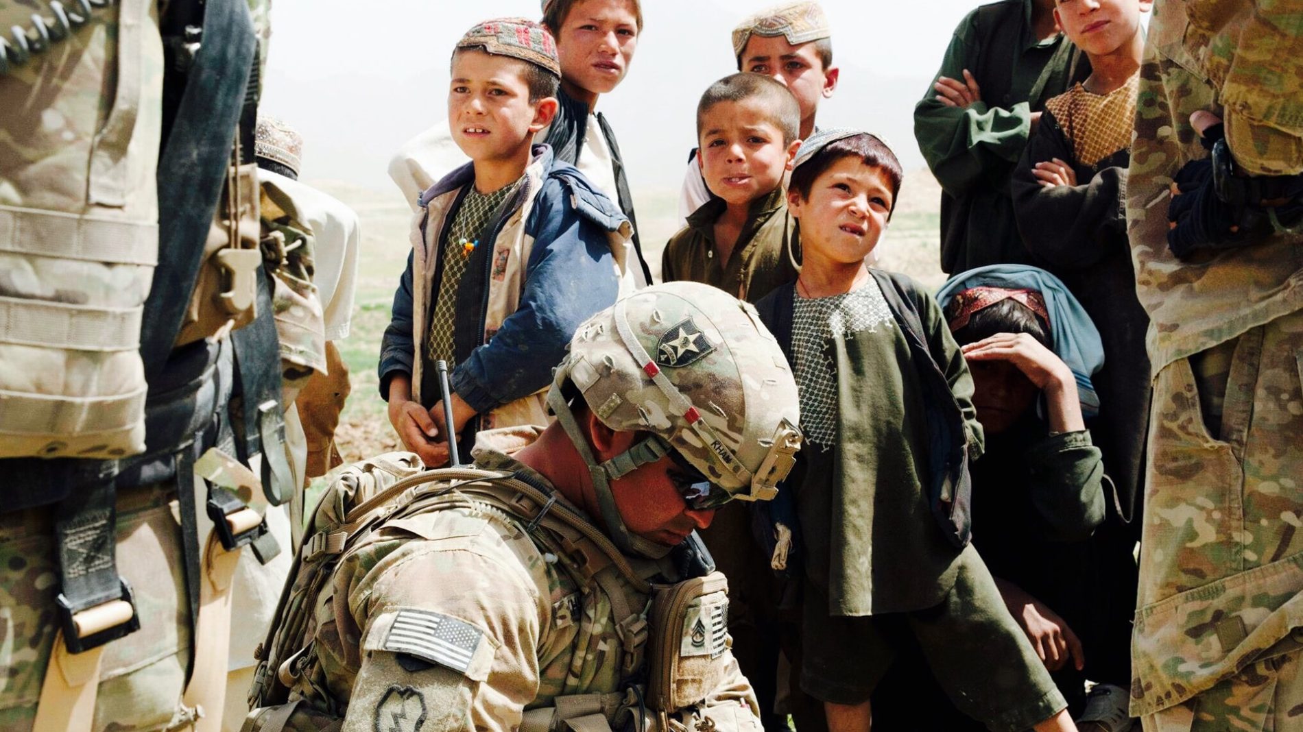 Soldier surrounded by afghan children longest war