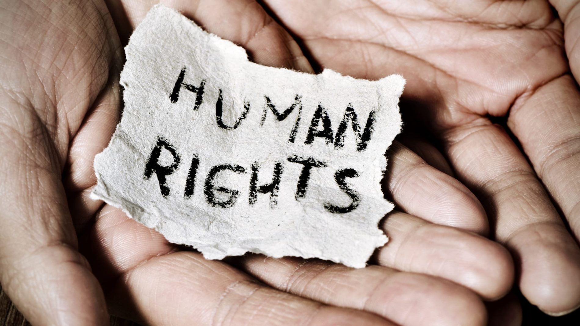 hands holding piece of paper saying HUMAN RIGHTS