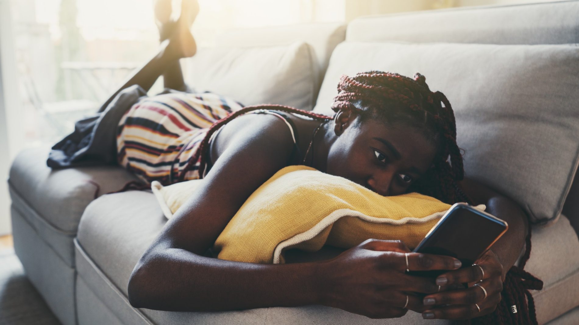Photograph of a person lying on the couch and looking at their phone
