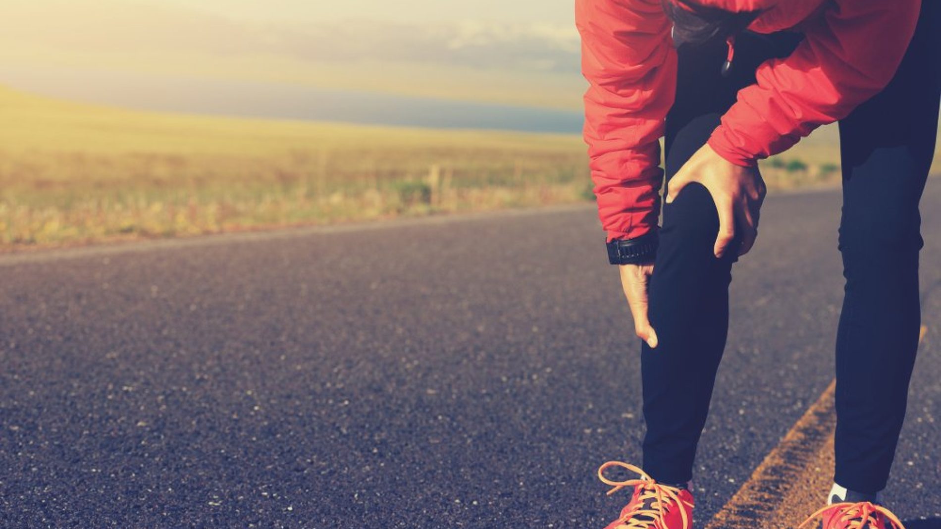 woman runner hold her injured leg on road