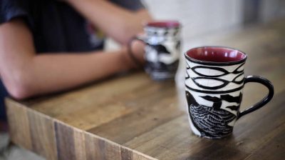 Photo of a person sitting at a table with two mugs in front of them