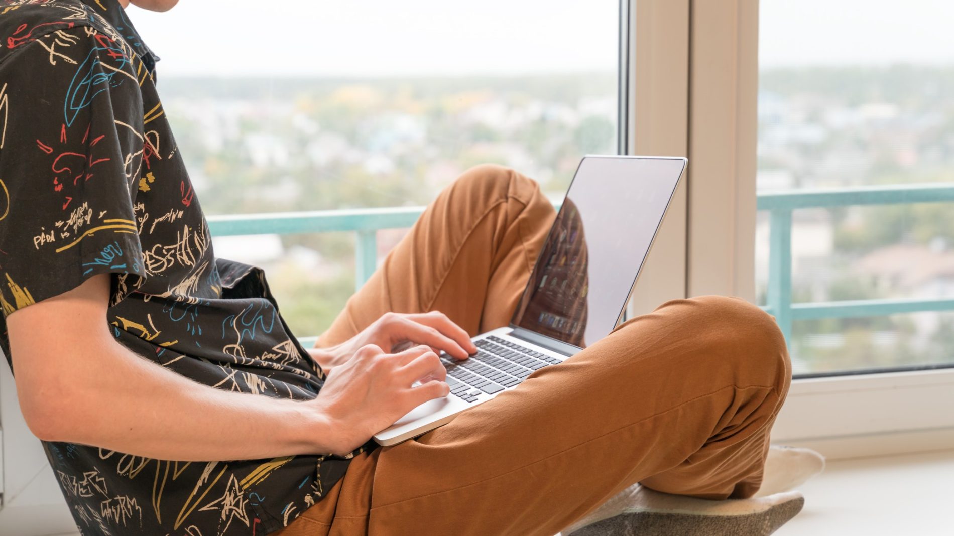 photo of a person sitting on a windowsill on their laptop - emergency tax