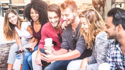 group-sitting-on-wall-looking-at-phone-Da7kd9