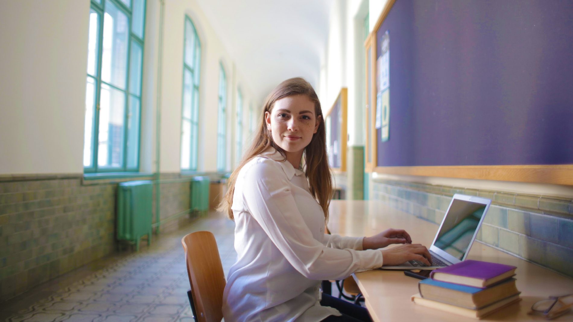 leaving cert Female student typing on laptop in university hallway
