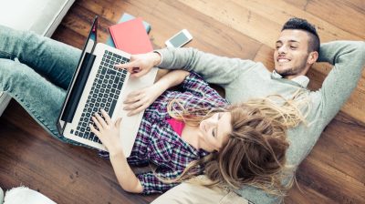 Girl and guy laying on ground looking at computer screen
