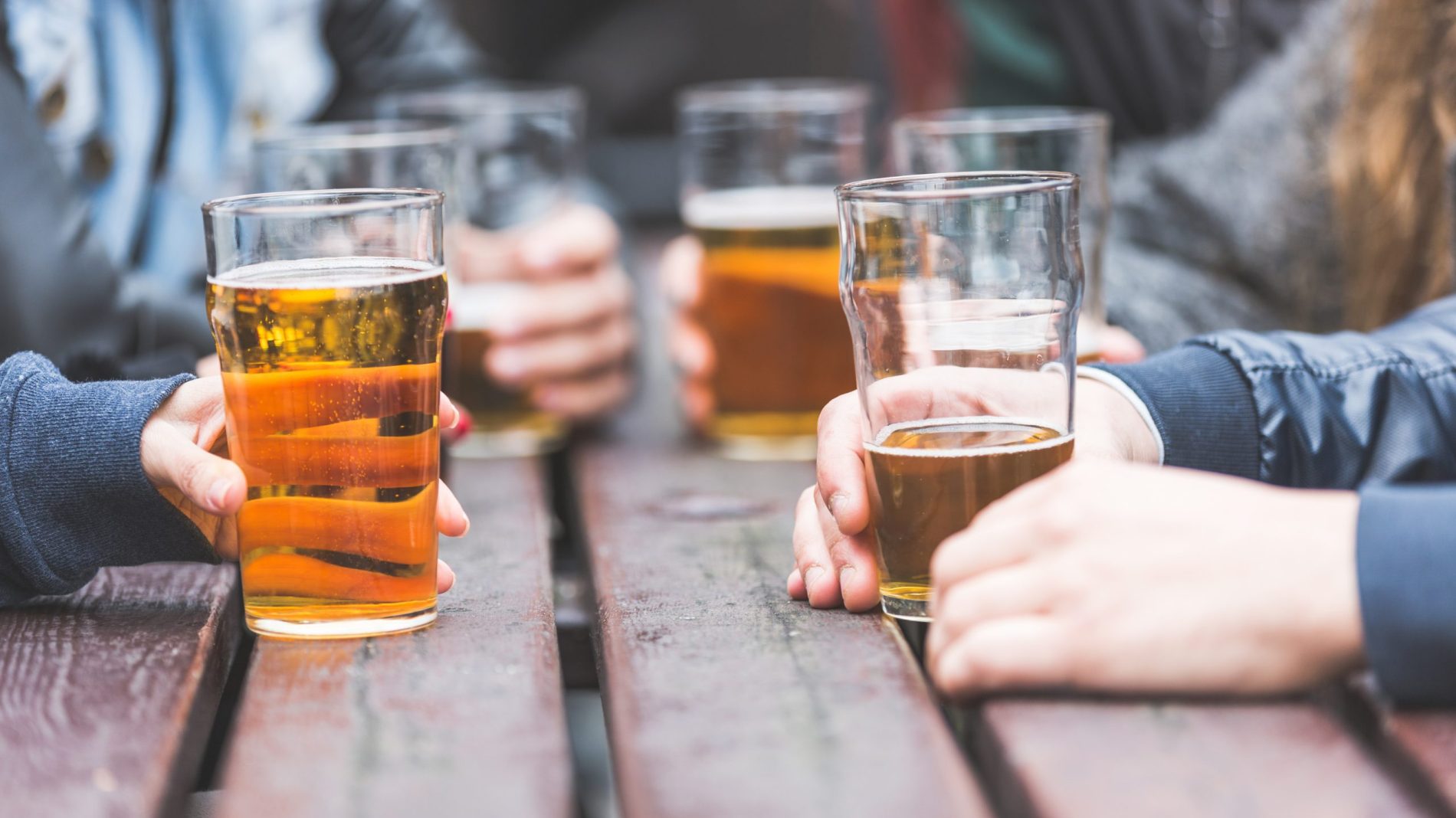 Hands holding glasses with beer on a table in London