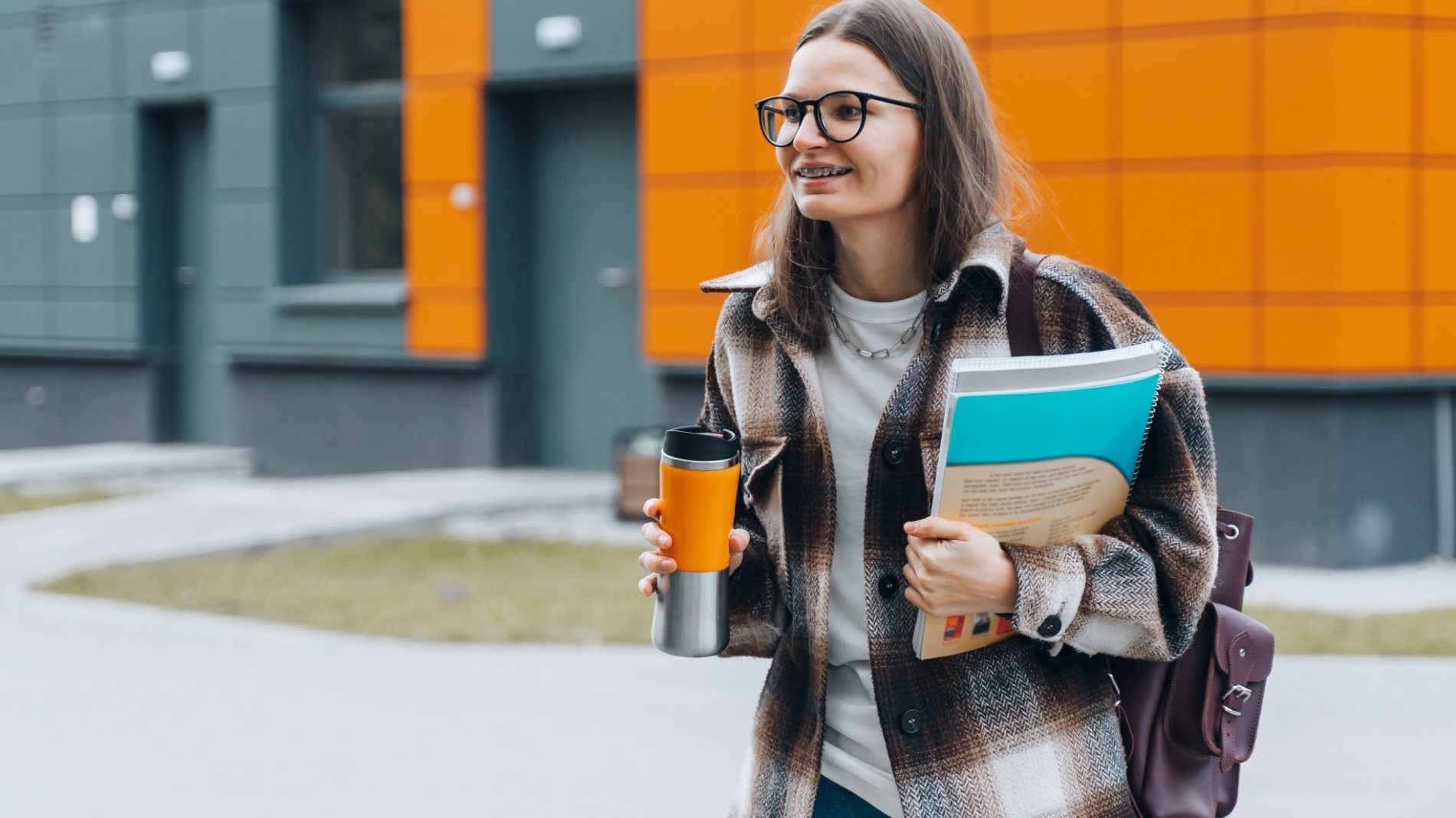 Student walking on a campus with coffee and books - going to college with an invisible disability