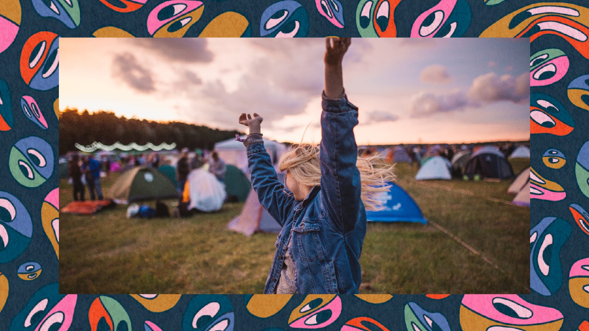 A person raising their arms in the air in front of tents at a music festival