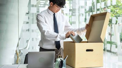 Ohoto of a person packing items on their desk into a cardboard box - lose job