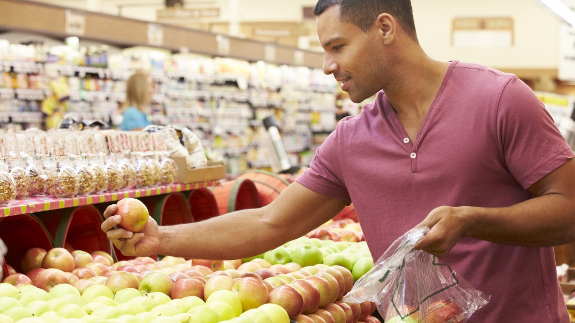 A man holding an apple in a supermarket