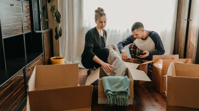 Photo of two people sitting on floor while packing cardboard boxes