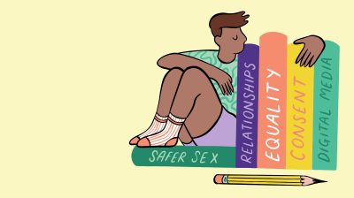 a masculine person sits beside books titled 'safer sex', 'relationships', 'equlaity', 'consent', 'digital media' all topics on new sex education ireland programme