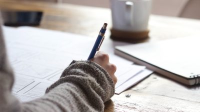 a close up of a person writing in a notebook with a pen
