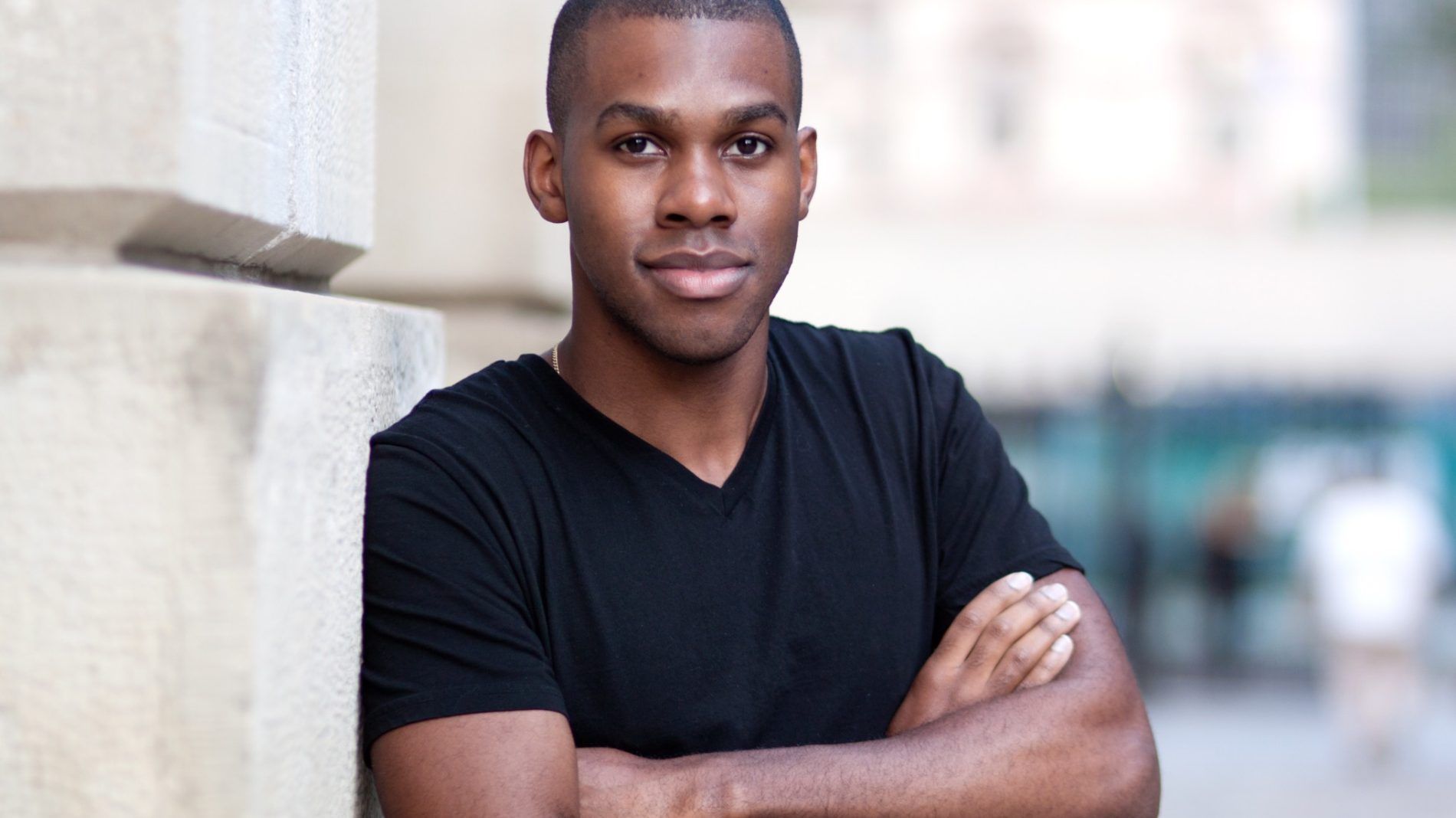 A young Black person leaning against a wall