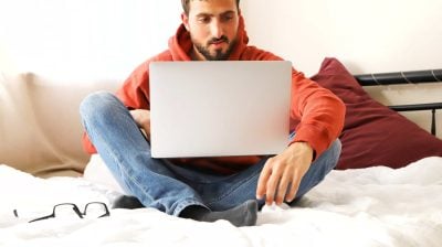 Man sitting on bad using laptop