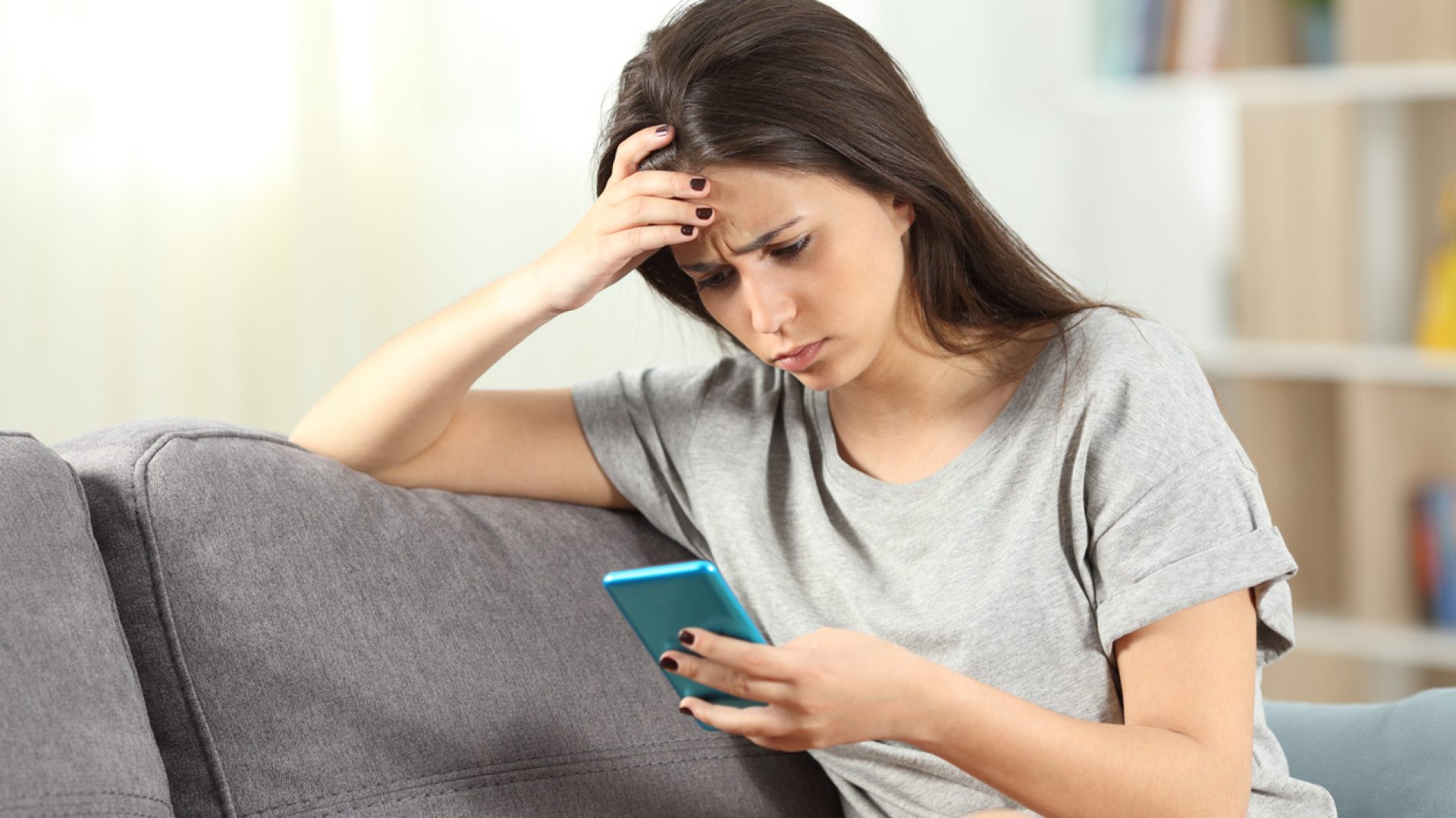 Sad teen reading bad news in a smart phone