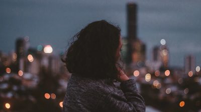 A young woman looking into the distance in front of a city skyline