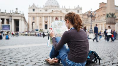 Photo of a person sitting on the ground in a city looking at a map