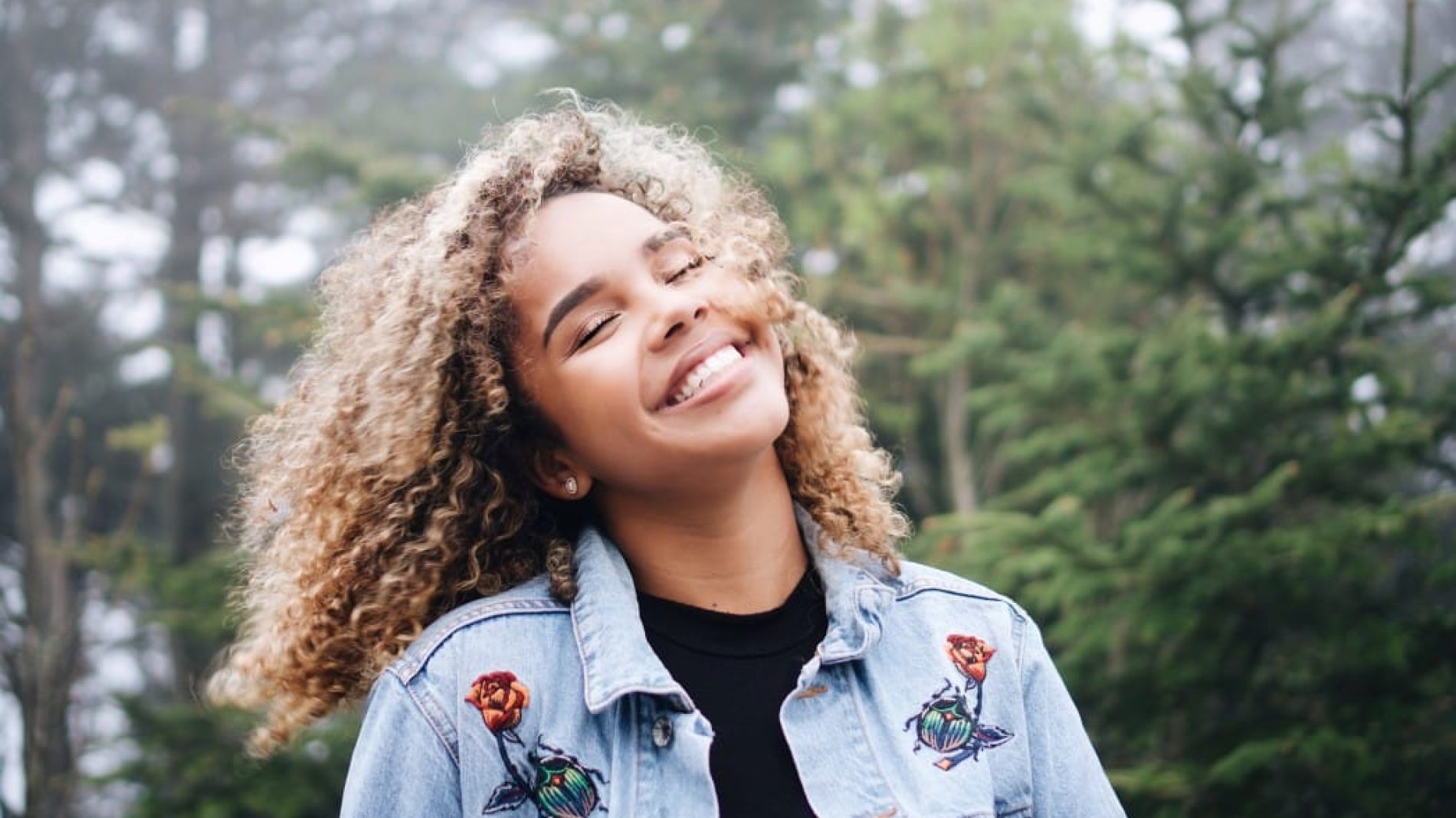 Happy smiling woman with curly hair wearing jean jacket spunout impact video