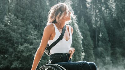 feminine person riding a wheelchair looking hopeful at the edge of a forest support PTSD
