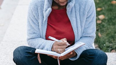 person sits cross legged writing into a journal anxiety depression