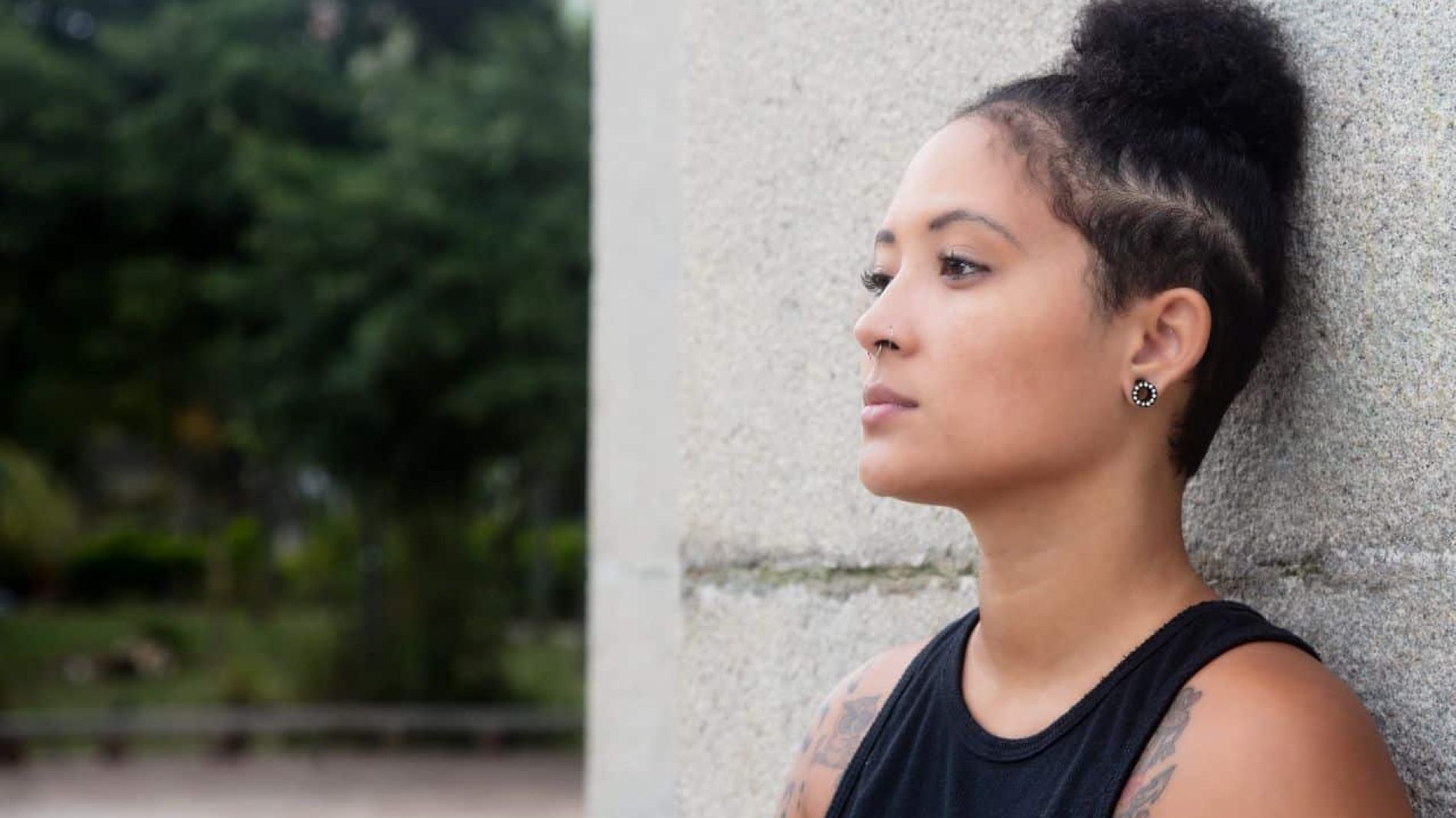 Young woman standing against a wall looking thoughtful